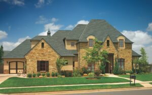 Elegant stone house with newly installed asphalt shingle roof by Augustine Roofing