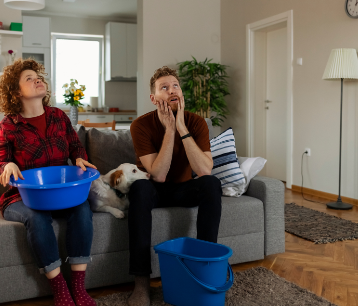 Couple gathering water buckets for leaky roof