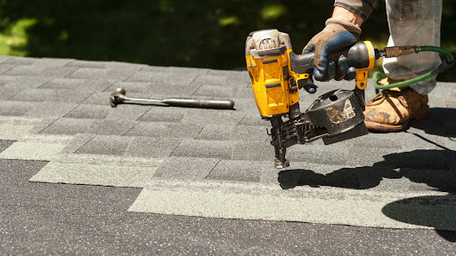 Roofer installing shingles with power tool