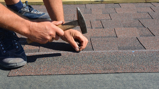 Contractor hammering nails into new roof